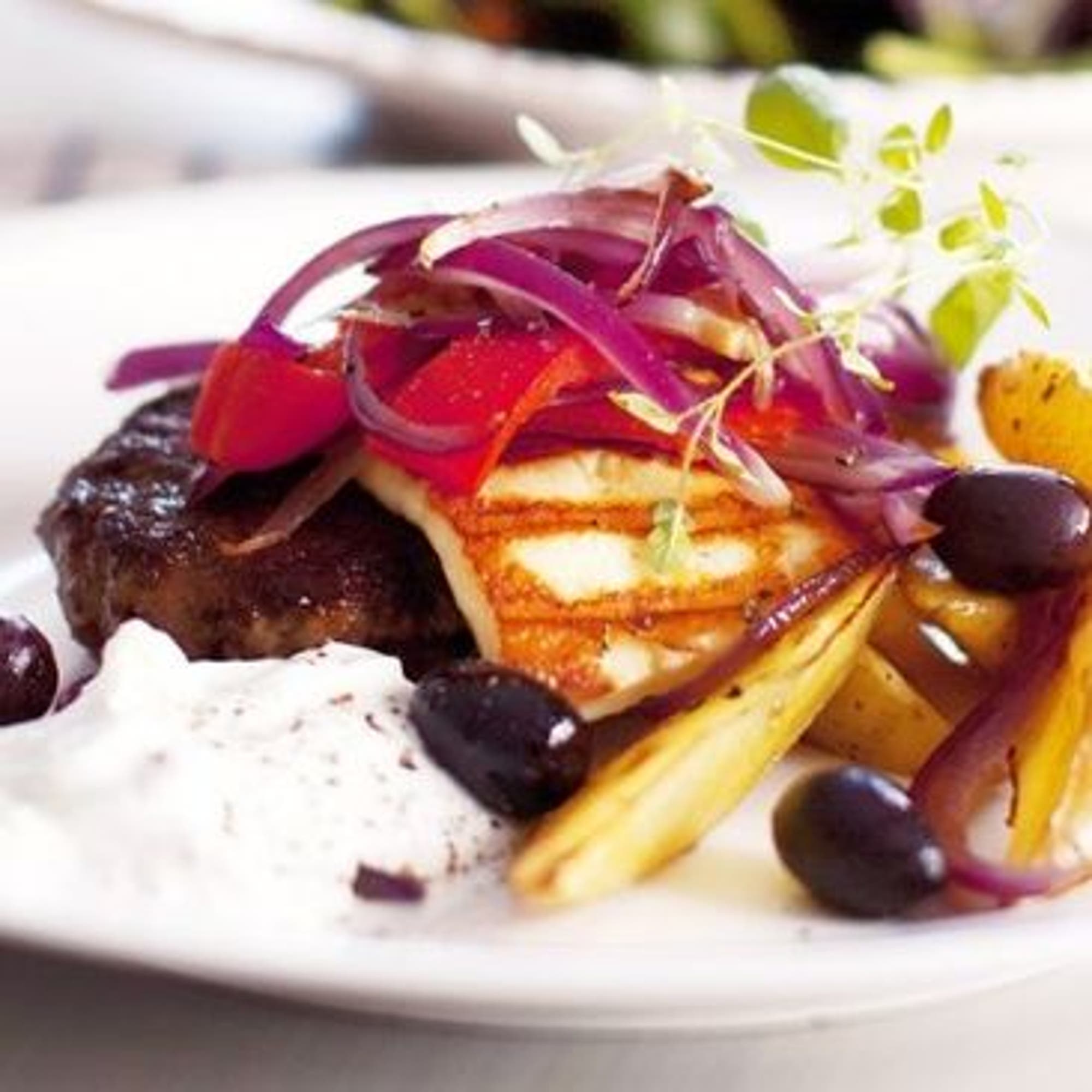Köttfärsbiffar med grilloumi, stekt lök, tzatziki och kalamataoliver