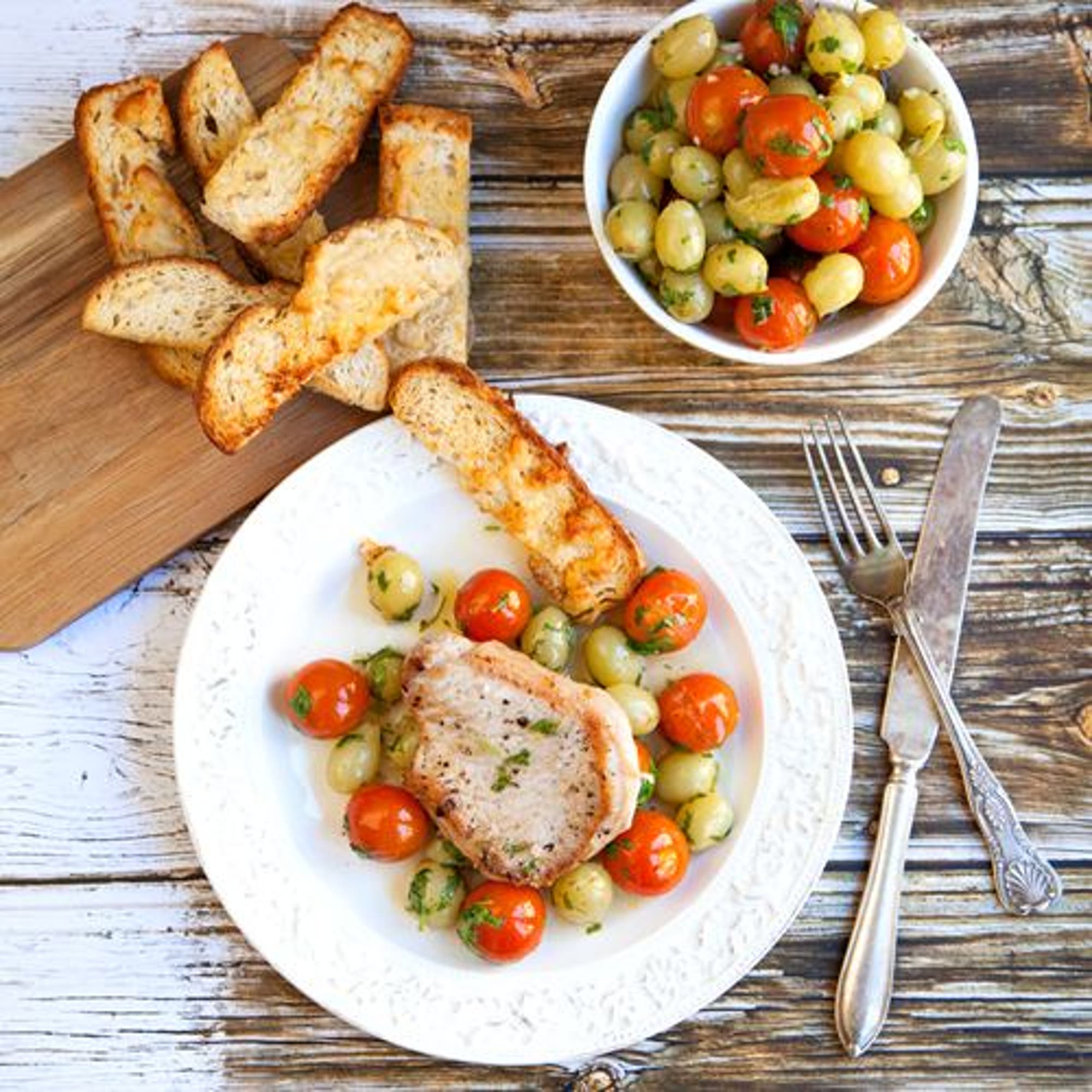 Tinas fläskkotletter med varma tomater, druvor och parmesanbröd