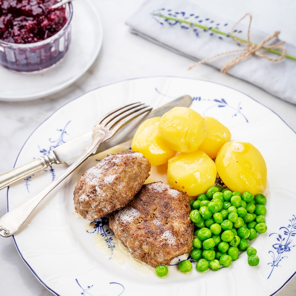Wallenbergare med kokt potatis, gröna ärtor och brynt smör